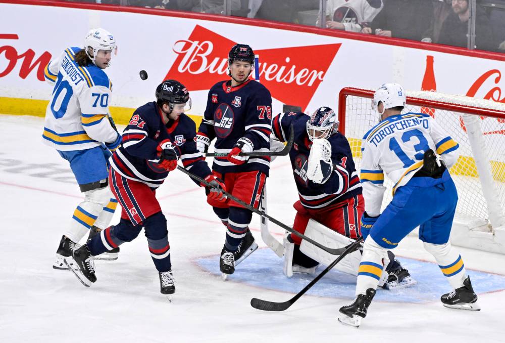 FRED GREENSLADE / THE CANADIAN PRESS
St. Louis Blues’ Oskar Sundqvist (70) and Alexey Toropchenko (13) look for the rebound as Winnipeg Jets’ Isak Rosen (27) and Jacob Bryson (78) defend in front of goaltender Eric Comrie (1) during the third period in Winnipeg on Sunday.