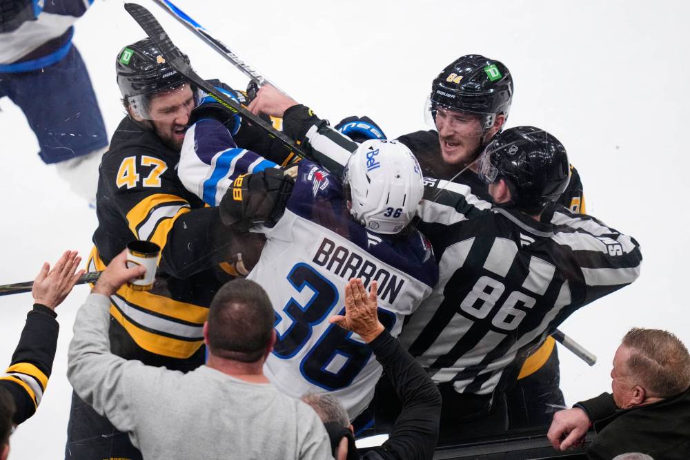 Charles Krupa / The Associated Press
Boston Bruins' Mark Kastelic, left and Tanner Jeannot tangle with Winnipeg Jets' Morgan Barron in the second period, Thursday.