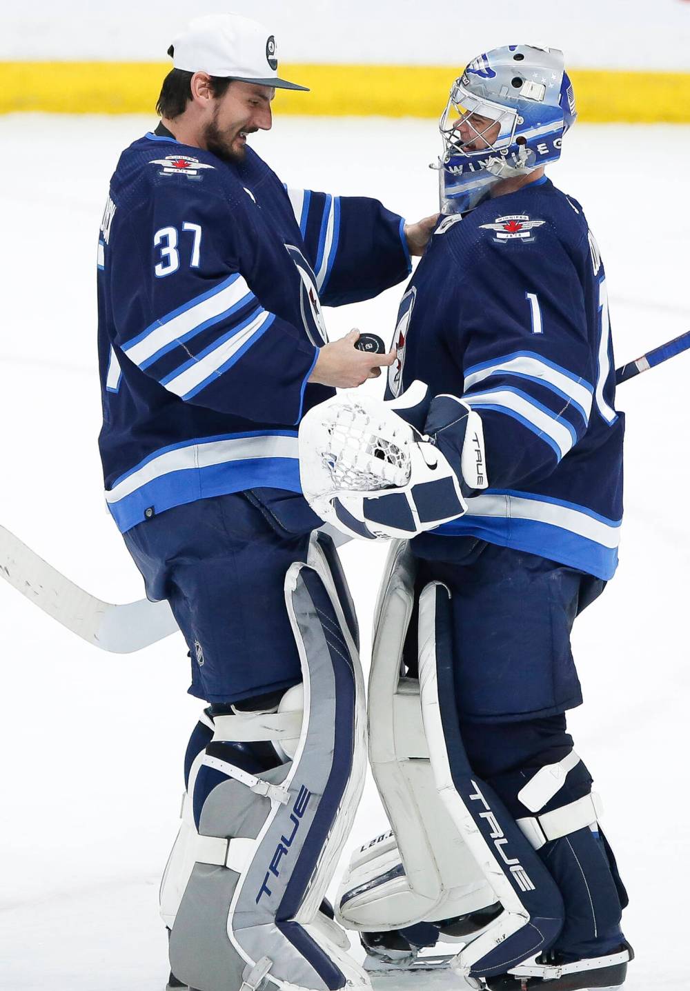 JOHN WOODS / THE CANADIAN PRESS FILES
Winnipeg Jets goaltender Connor Hellebuyck, left, congratulates teammate Eric Comrie on his first NHL shutout after a game in 2022.