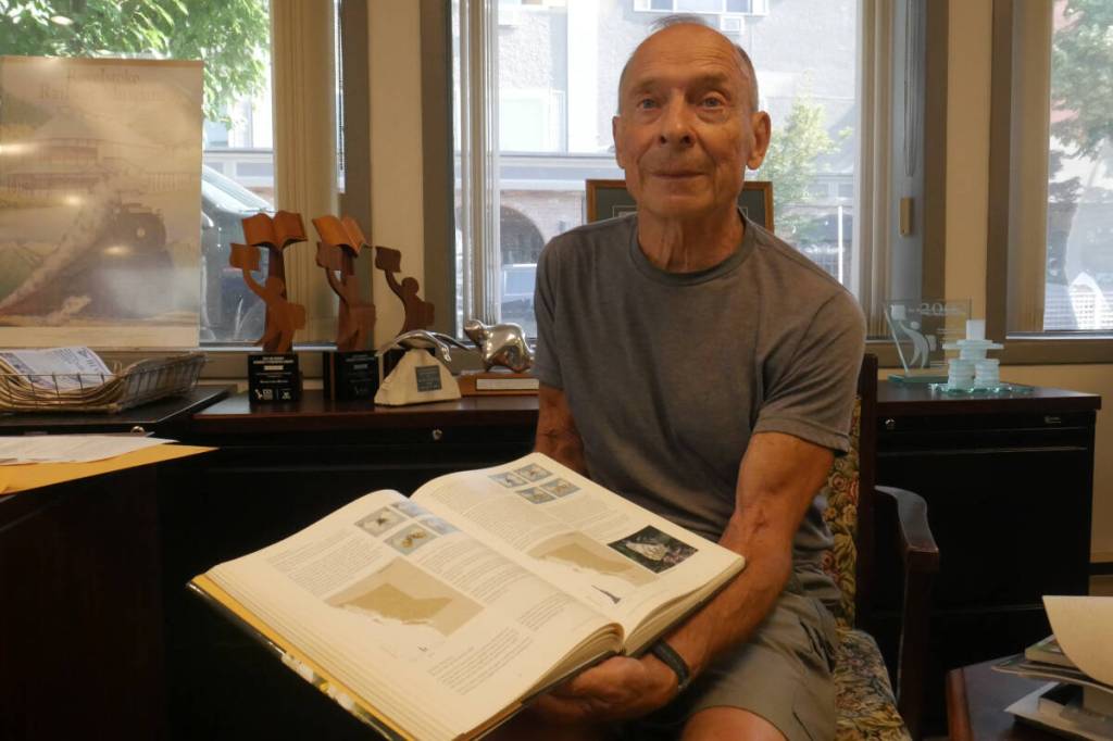 Dave Threatful, 80, at the Revelstoke Review office Sept. 11, 2025, with a copy of Butterflies of British Columbia, which was published in 2001 and references his namesake species, Polygonia oreas threatfuli. (Evert Lindquist/Revelstoke Review)