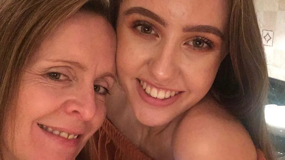 Beth taking a selfie with Emily. They're both smiling, with the picture being taken in a kitchen.