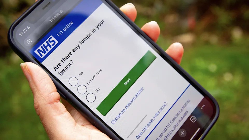 A person is holding a phone which is on the NHS 111 online service. It has a multiple choice question which reads: Are there any lumps in your breast?