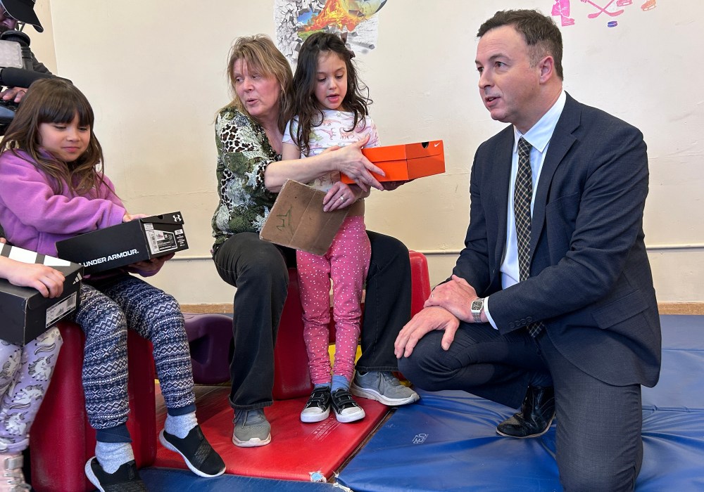 Manitoba Finance Minister Adrien Sala hands out shoes to children at Linwood Childcare Centre in Winnipeg on March 20, 2026. This is part of a pre-budget news conference on child care funding. THE CANADIAN PRESS/Steve Lambert