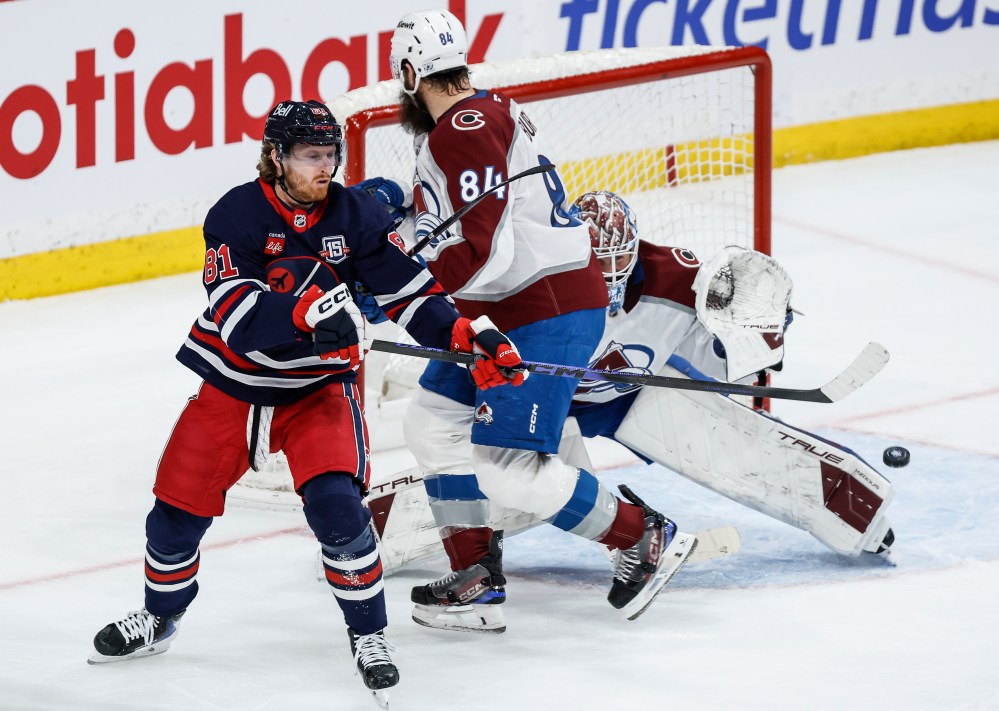 Winnipeg Jets' Kyle Connor (81) tries to tip the puck past Colorado Avalanche goaltender Mackenzie Blackwood (39) as Brent Burns (84) defends during third period NHL action in Winnipeg, Saturday, March 14, 2026. THE CANADIAN PRESS/John Woods