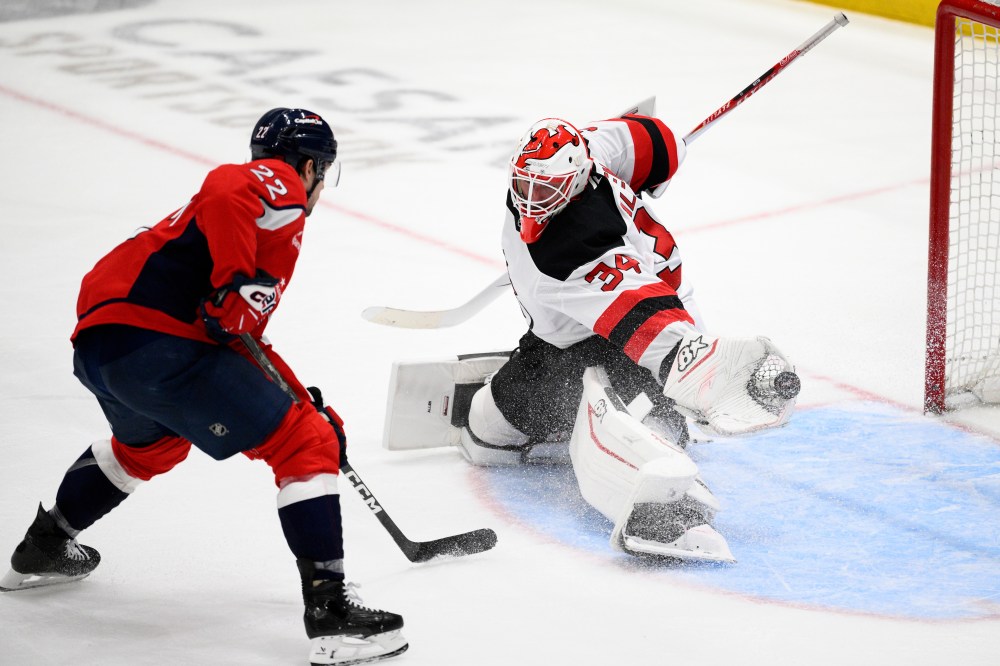 New Jersey Devils goaltender Jake Allen (34) reaches for the puck against Washington Capitals left wing Brandon Duhaime (22) during the third period of an NHL hockey game Friday, March 20, 2026, in Washington. (AP Photo/Nick Wass)