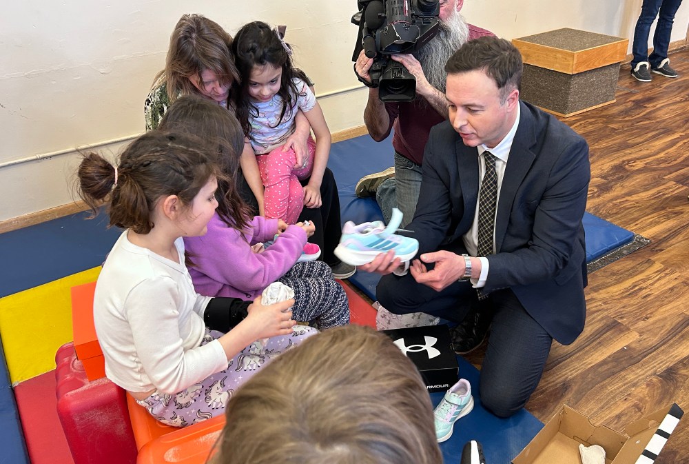 Manitoba Finance Minister Adrien Sala hands out shoes to children at Linwood Childcare Centre in Winnipeg on March 20, 2026, as part of a pre-budget news conference on child-care funding. THE CANADIAN PRESS/Steve Lambert