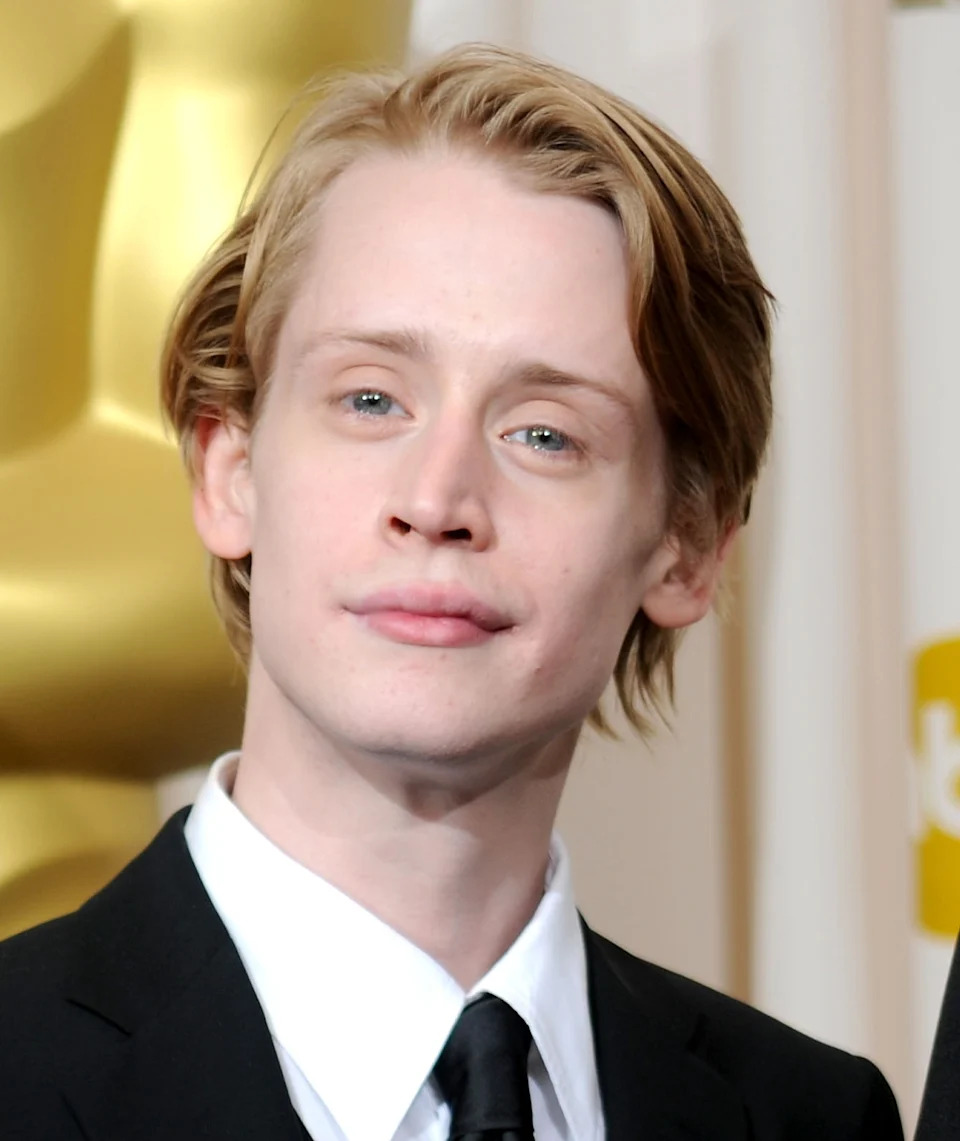 Macaulay Culkin with light hair wearing a formal suit and tie at an event