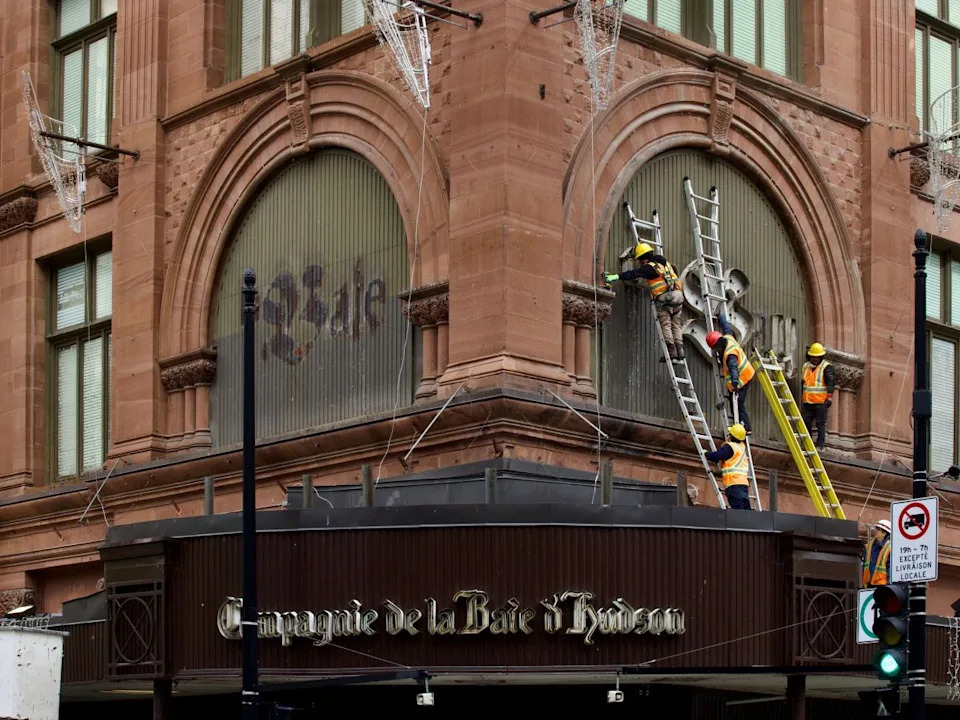  Four workers on ladders are seen dismantling the iconic sign for The Bay in downtown Montreal on Monday, March 9, 2026.