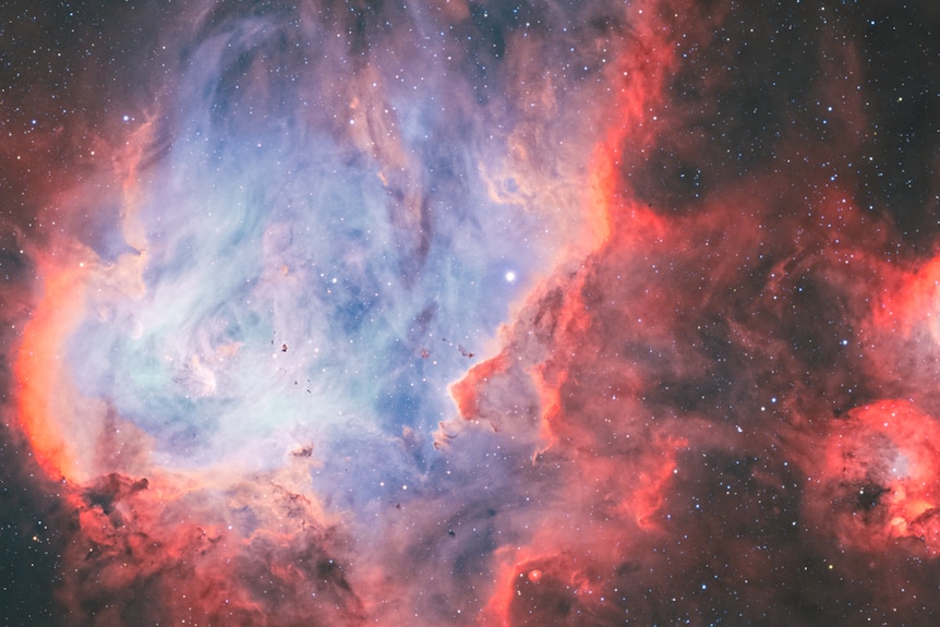 A red, blue and white photo of a nebula in space as seen through a telescope.