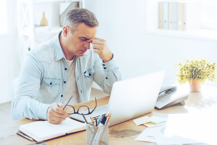 A person frustrated and upset sitting in front of a computer.