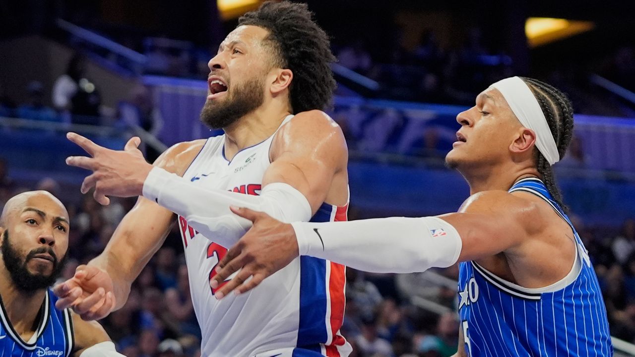 Detroit Pistons guard Cade Cunningham, center, loses control of the ball as he tries to go between Orlando Magic guard Jevon Carter, left, and forward Paolo Banchero during the first half of an NBA basketball game, Sunday, March 1, 2026, in Orlando, Fla. (AP Photo/John Raoux)