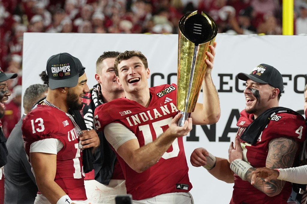 Fernando Mendoza and other football players celebrating with a trophy.