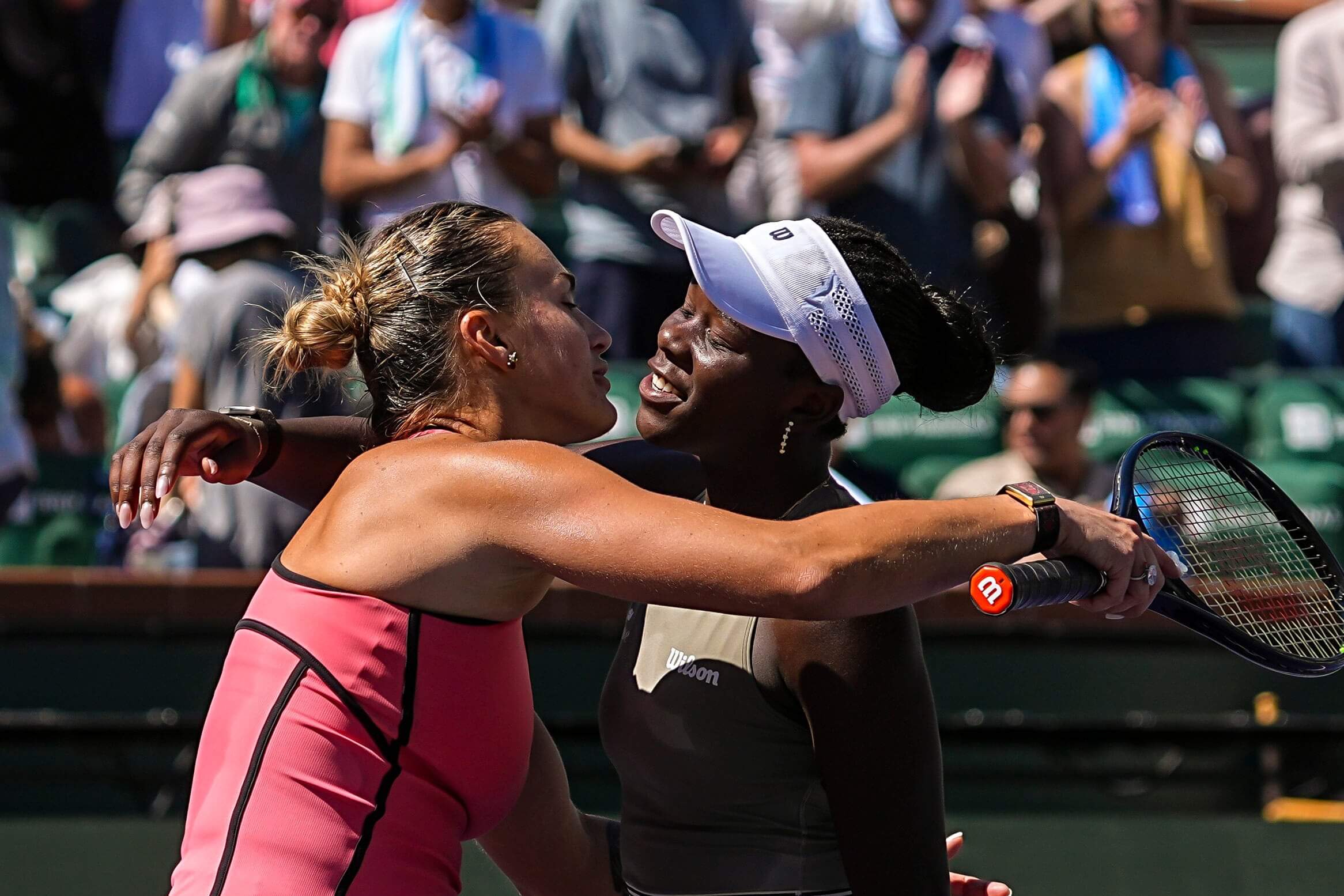 Aryna Sabalenka (left) and Victoria Mboko (right) embrace at the end of a tennis match.