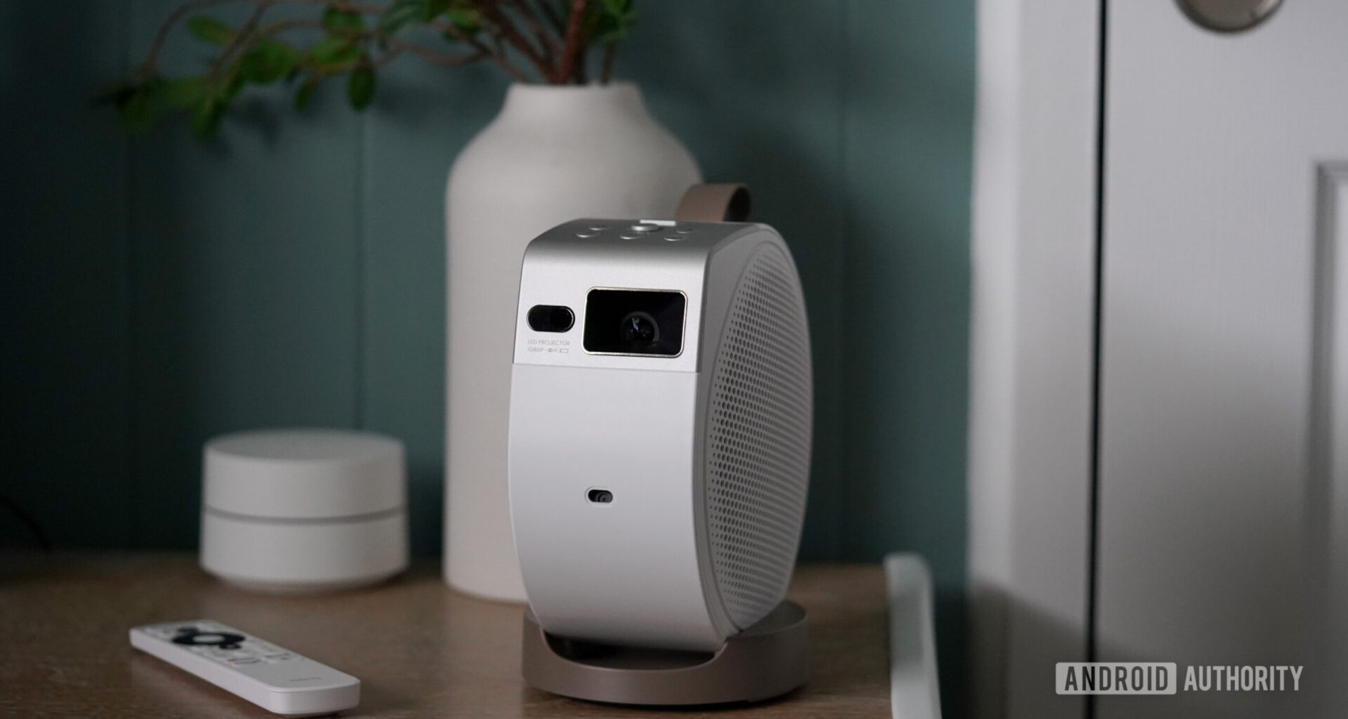 A BenQ GV32 projector rests on a wooden surface alongside its remote.