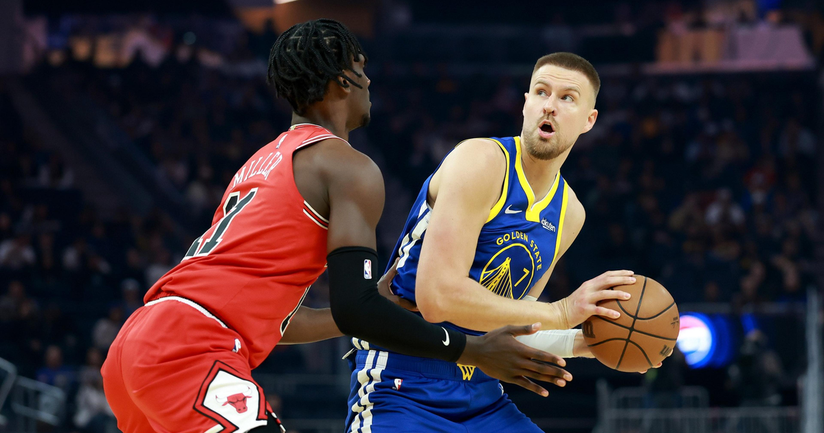 A Golden State Warriors player holds a basketball while being closely guarded by a Chicago Bulls player during a game.