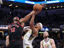 Indiana Pacers guard Andrew Nembhard, right, shoots around the defense of Toronto Raptors forward Collin Murray-Boyles during the first half of an NBA basketball game in Indianapolis.
