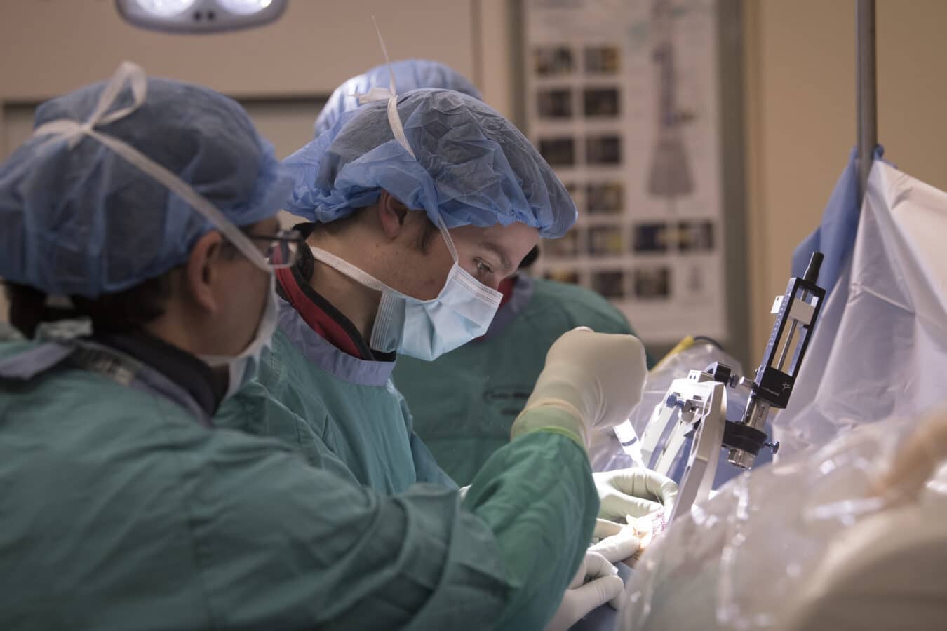 A close-up of two doctors wearing surgical scrubs, performing a deep brain stimulation procedure.