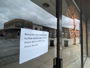 A cafe with a sign in the window announces it's closed during ongoinn precautionary boil water advisory