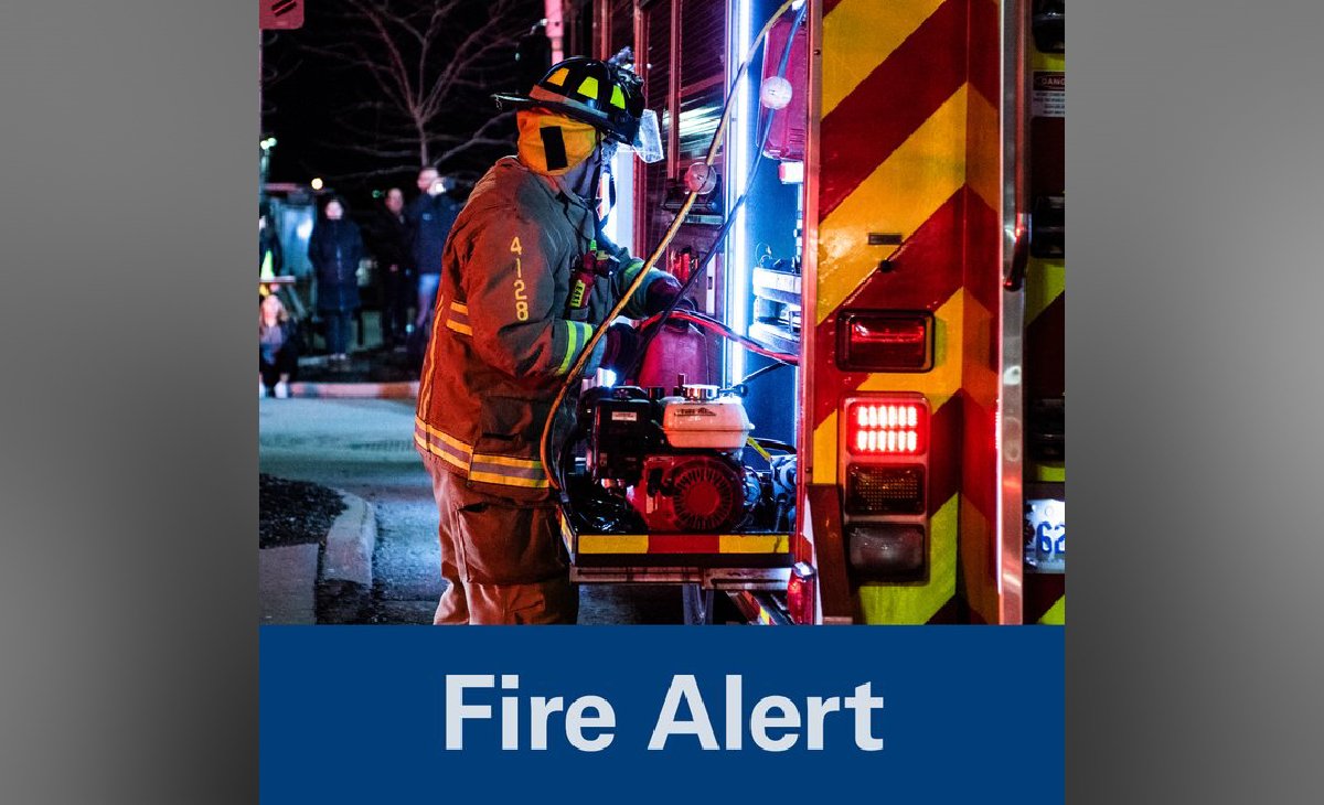Firefighter beside a fire truck with emergency lights on at night.