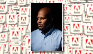 A man in a light blue button-down shirt looks to the side against a dark background. Behind him, there is a blurred collage of Adobe logos in red and white.