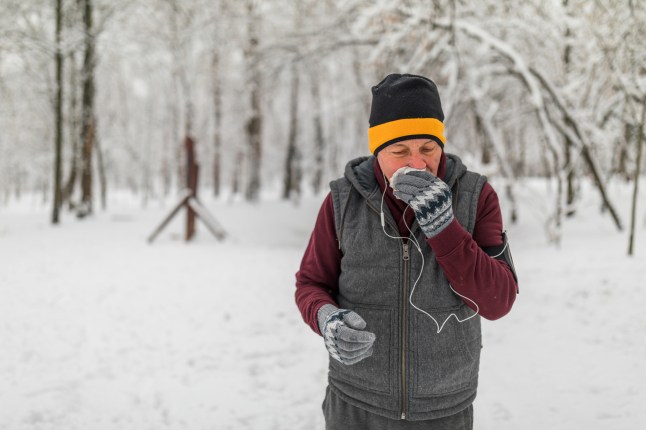 Man blows his nose while jogging in the snow.