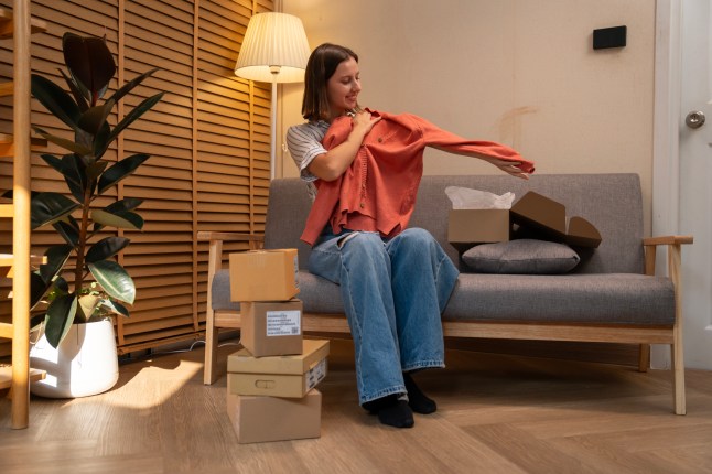 Young Woman Unboxing A Package With A New Shirt She Ordered Online