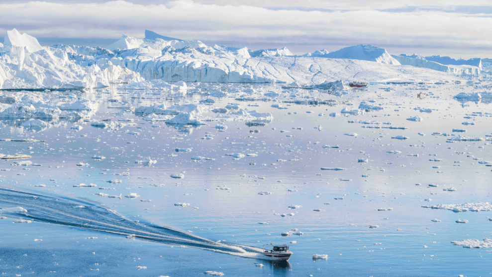 A boat sails through light blue, ice-specked water.