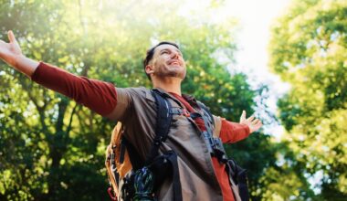 Happy man with stretching out arms in nature