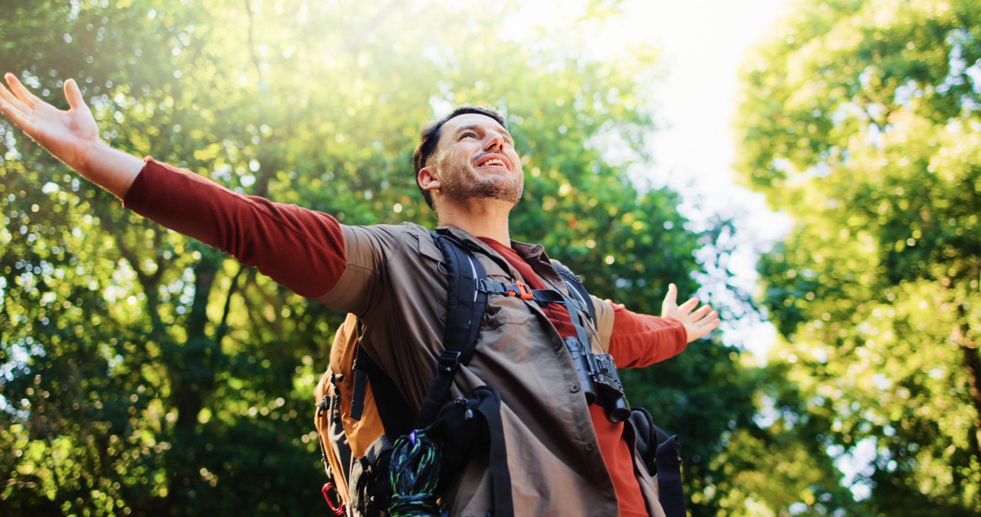 Happy man with stretching out arms in nature