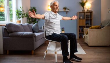 man sits on chair mid exercise with arms extended out