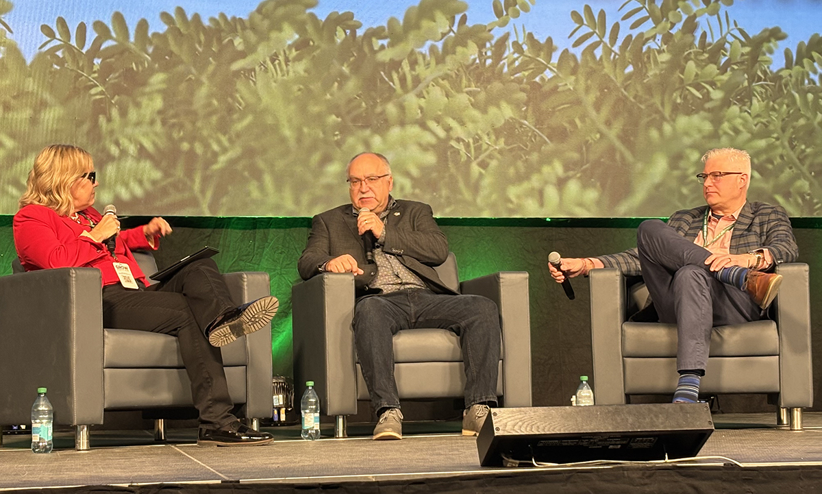 Three people, two men and a woman, sit in chairs on a stage at Canada's Farm Show in Regina, Saskatchewan, discussing provincial budget released yesterday.
