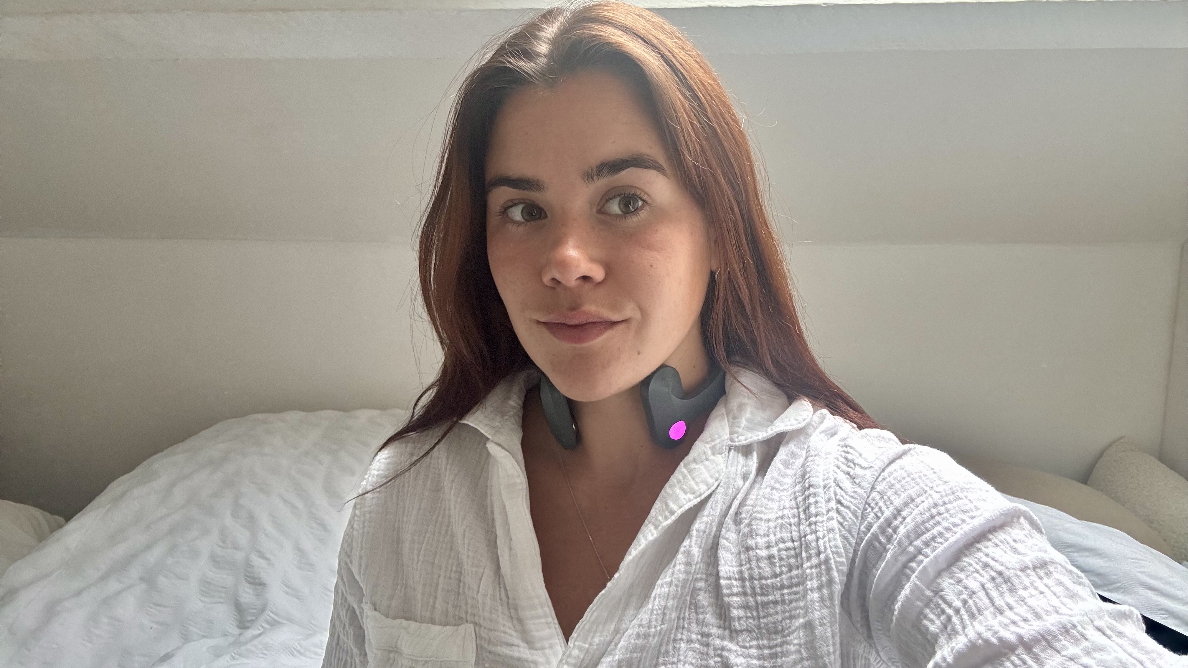 A girl wearing Pulsetto vagus nerve stimulator on neck and white pyjama shirt