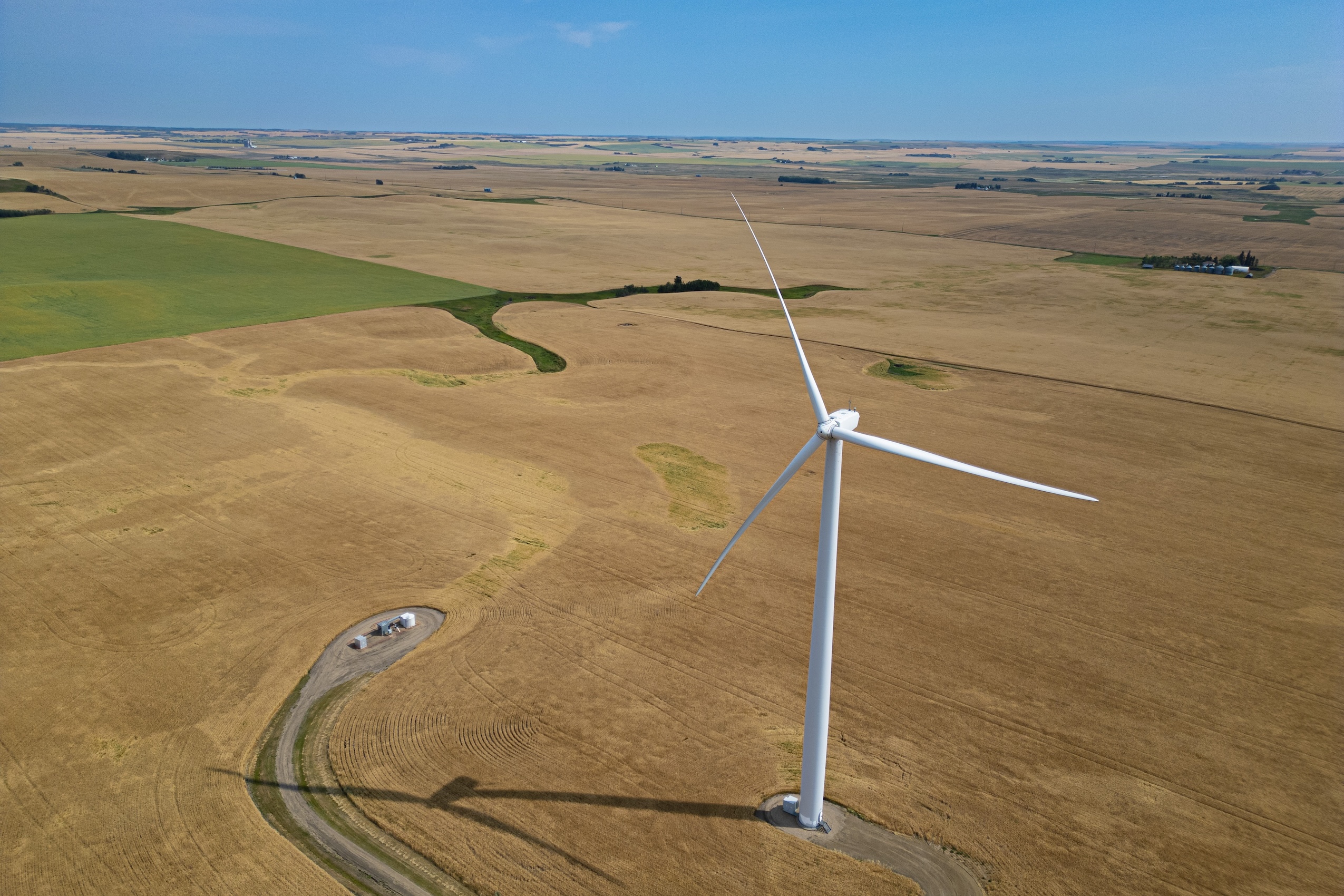 An overhead view of a massive wind turbine in a sprawling prairie farm landscape