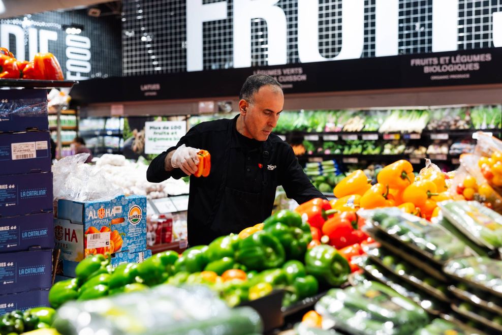 A man sorts through vegetables at a store.