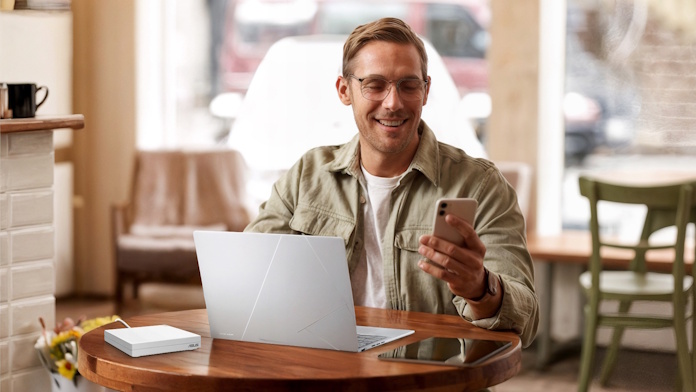 A man uses his laptop and smartphone, connected to the internet through the ASUS Z570 Go mini router