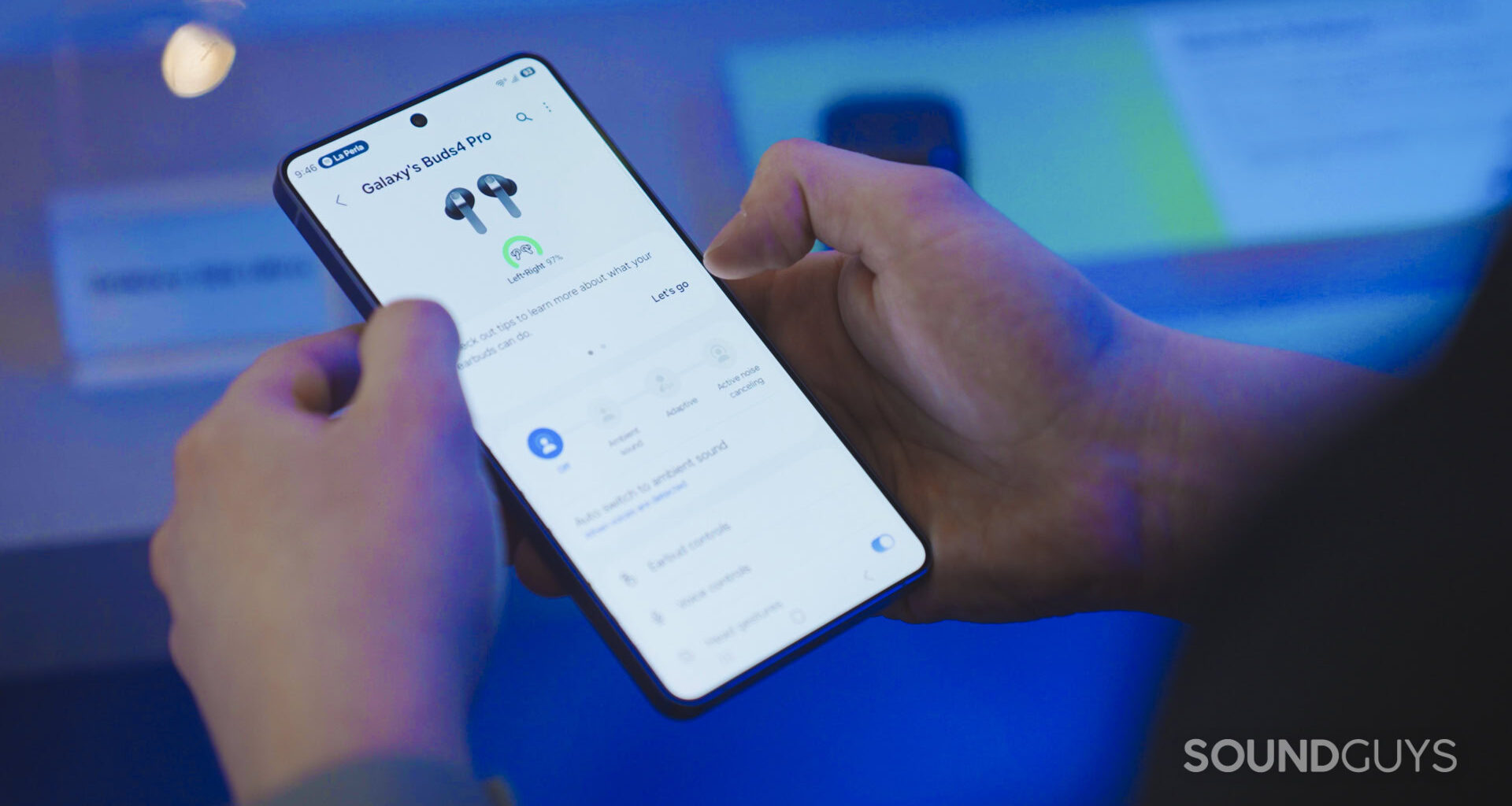 A man holds a new Samsung Phone while controlling the Gear Wearable app.