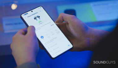 A man holds a new Samsung Phone while controlling the Gear Wearable app.
