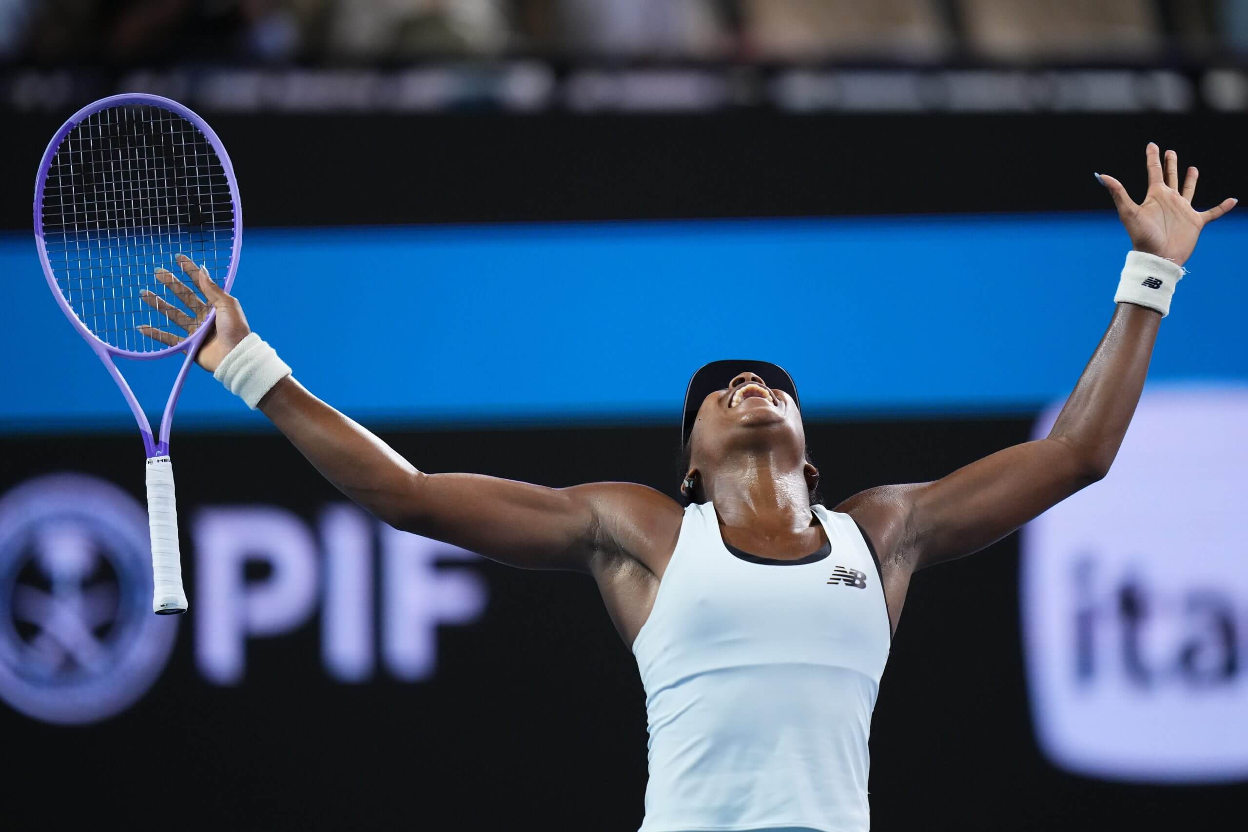 Coco Gauff raises her hands with her tennis racket in her right and yells out in celebration while looking at the sky.