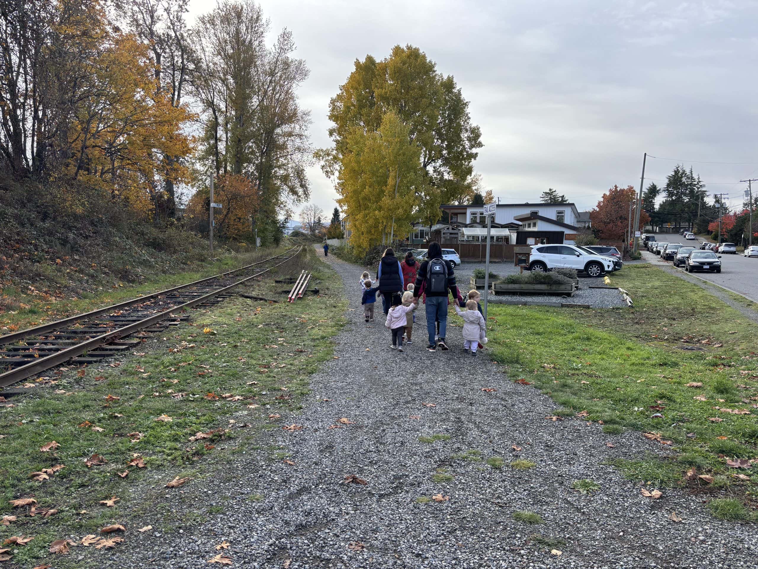 Kids walk away from the camera on a gravel path in a residential neighbourhood