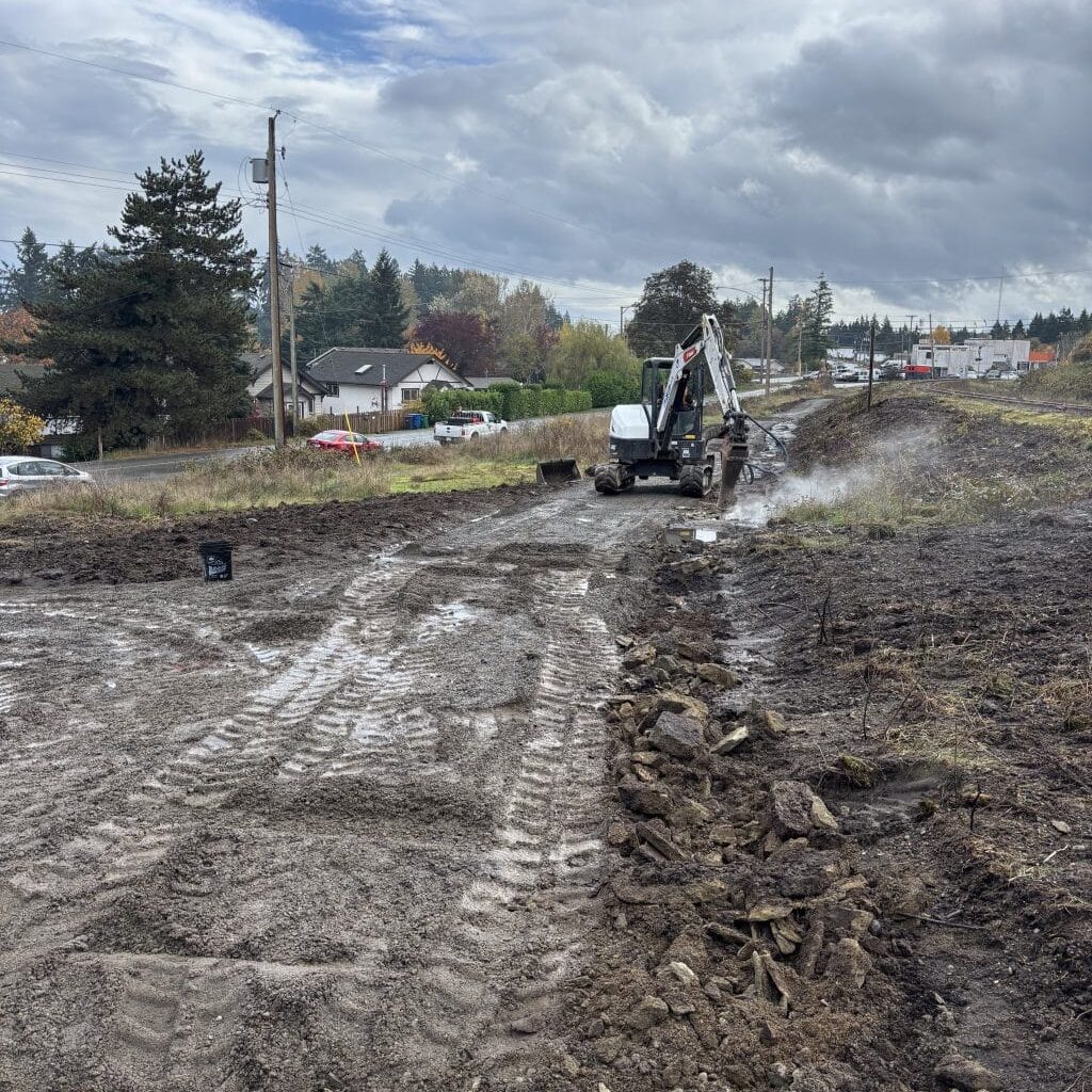 A muddy path in the foreground with a digger in the background