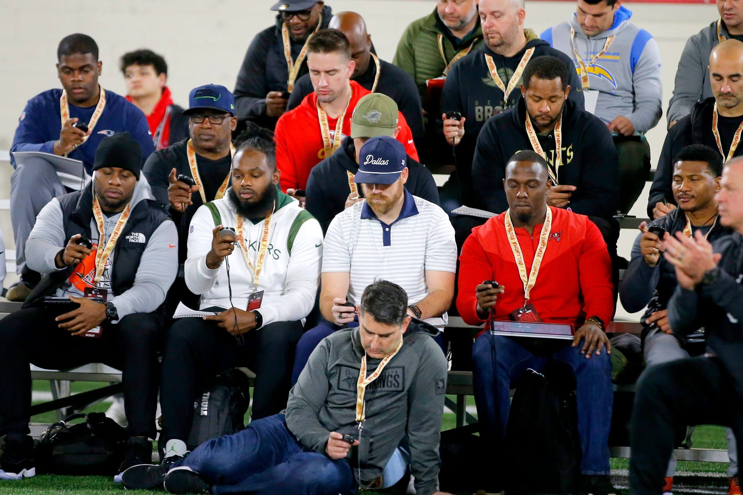 NFL scouts check their stopwatches during a University of Oklahoma pro day in 2022.