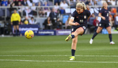 A player wearing a blue uniform kicks the ball on a soccer field
