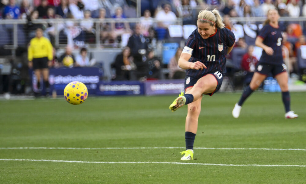 A player wearing a blue uniform kicks the ball on a soccer field