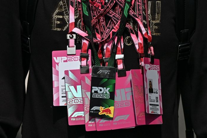 A person carries multiple VIP passes around their neck.