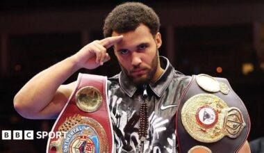 Moses Itauma salutes the camera with his belts around his shoulders