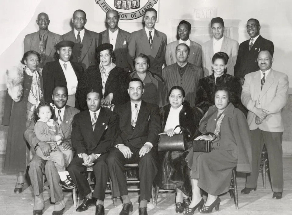 Members of the Brotherhood of Sleeping Car Porters, who worked for Canadian Pacific Railway, are photographed with their families in Calgary. Back row, L-R: P.T. Clay, Wilbur Milton, Jeff Bowen, Willis Richardson, 'Doomy' Hicks, Embert 'Amos' States, Melvin Crump. Middle row, L-R: Peaches Coleman, Willa 'Gotchie' Sneed, Louella Bellamy, Ethel Kay, Alex Kay, Rachel Walton, Charlie Walton. Front row, L-R: Ray Williams (holding Judy Williams), Odelle Holmes, Mr. Blanchette, Helen Braithwaite, Cordie Williams.