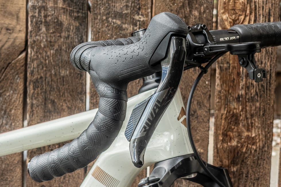 Bike handlebars with shifters, featuring textured grips and mounted cables.