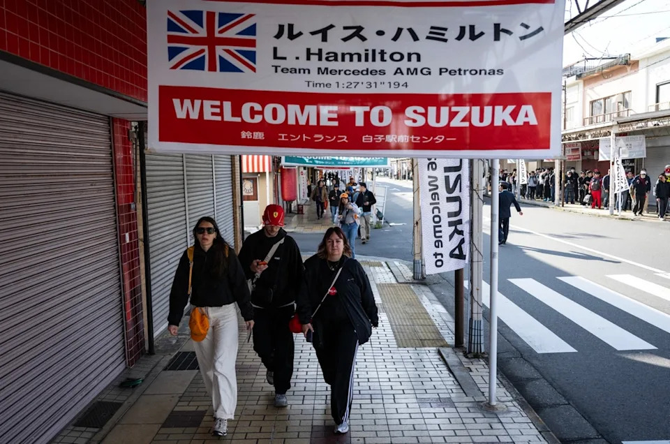 Fans line up near closed shops as they wait for a bus to the race track.