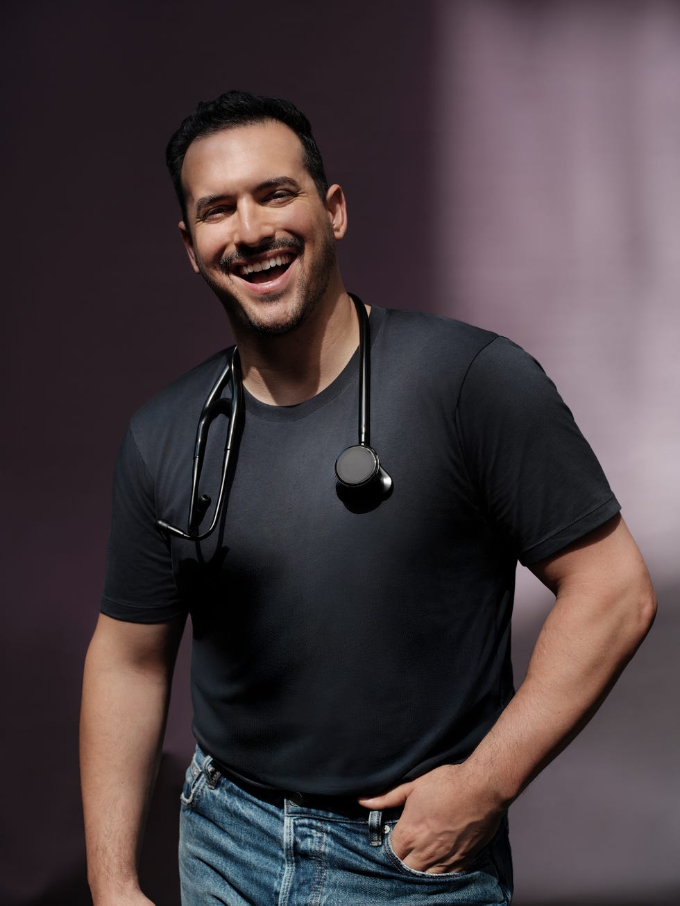 person in a dark shirt with a stethoscope around their neck