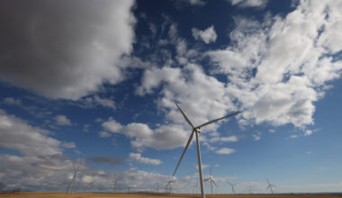 Windmills are seen on Alberta's prairie landscape, with clouds above.